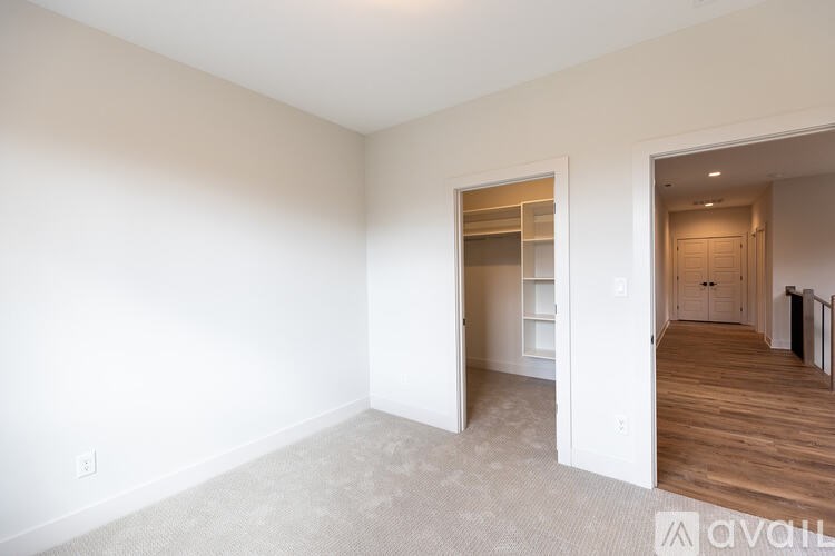 A spacious, empty room with a carpeted floor and white walls.
