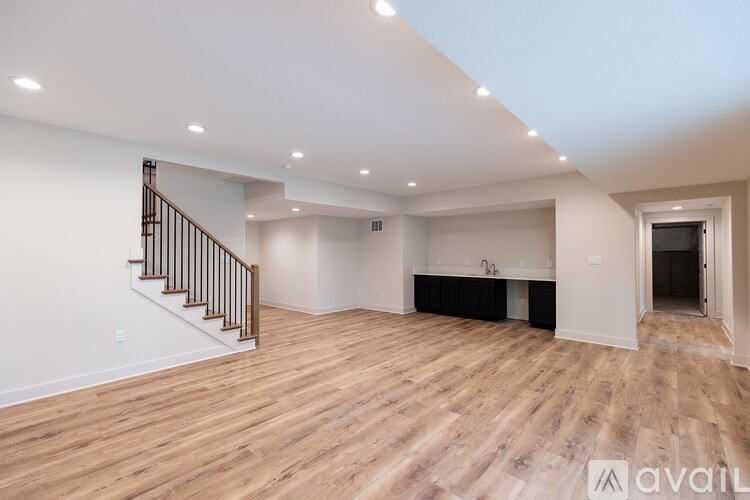 A spacious room with wooden flooring and a staircase.