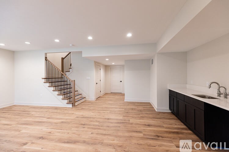 A spacious room with wooden floors and a staircase with a wooden railing.