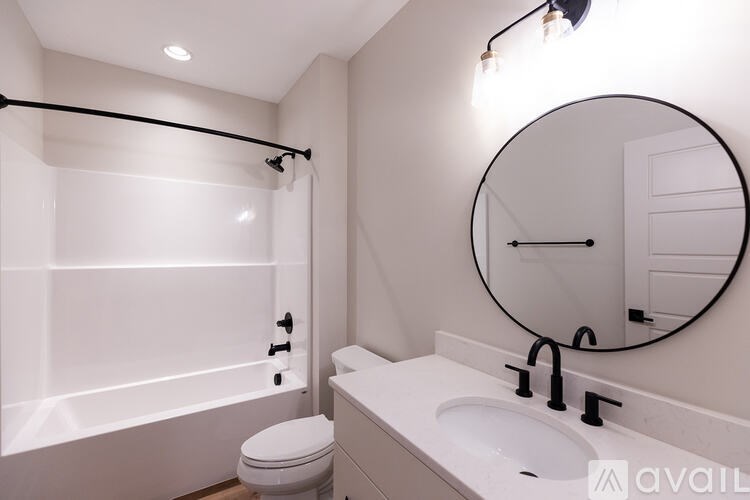 A bathroom with a toilet, sink, and a round mirror.