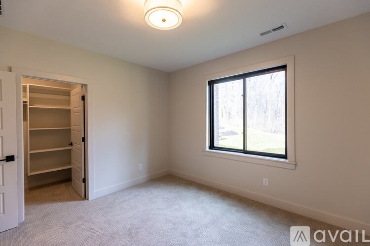 A room with a window and a carpeted floor.
