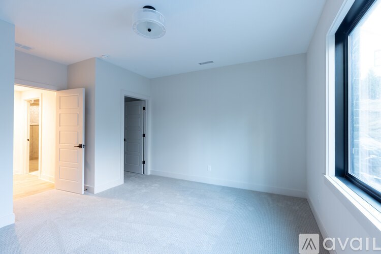A spacious, empty room with a smoke detector on the ceiling.