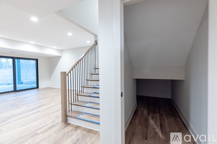 A wooden staircase with blue handrails leads to a brightly lit upper floor.
