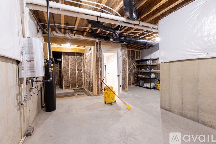 A room under construction with a lot of pipes and a yellow tool.