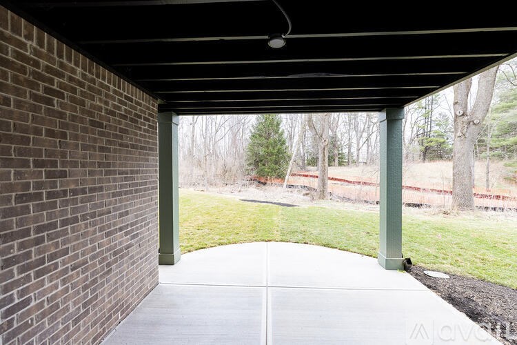 A patio with a brick wall and a green post.