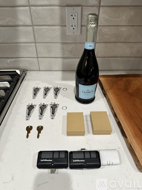A bottle of champagne sits on a counter with some tools and a key.