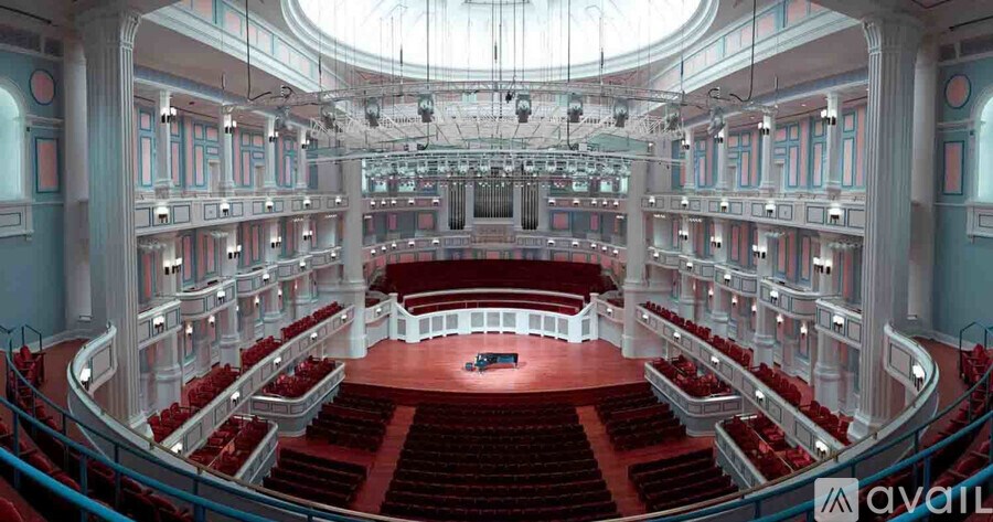 A large auditorium with red seats and a stage at the front.