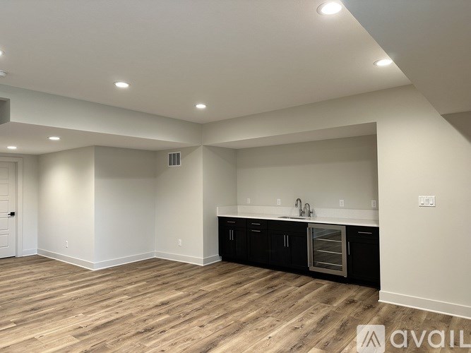 A spacious kitchen with wooden floors and black cabinets.