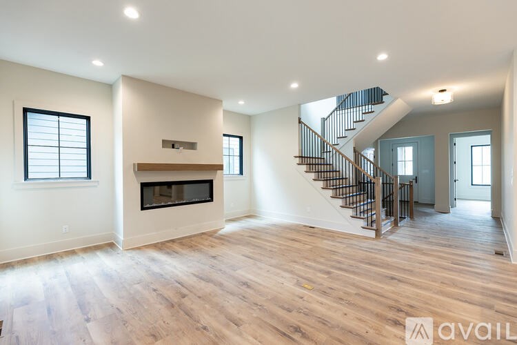 A spacious living room with a fireplace and a staircase.