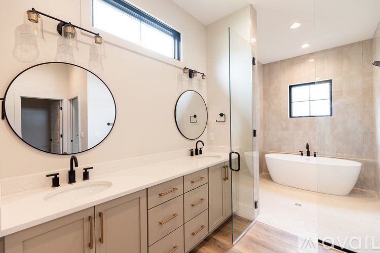 A modern bathroom with a large mirror and a bathtub.