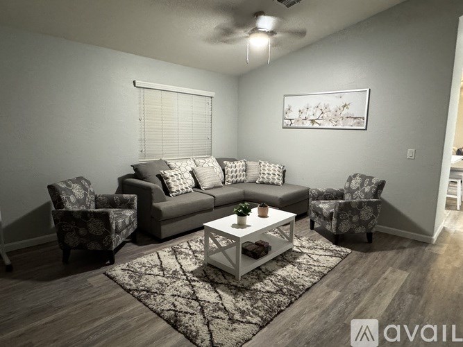 A living room with a grey couch, two chairs, and a coffee table.