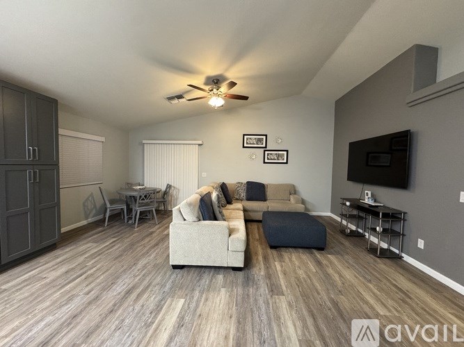 A living room with a grey couch and a television on the wall.