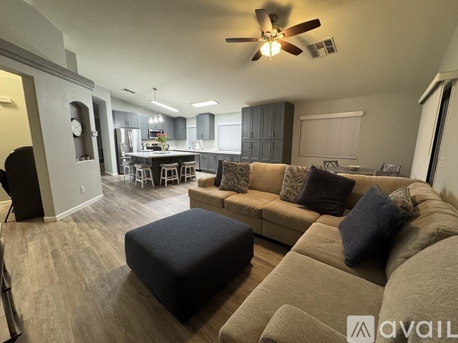 A living room with a brown couch and a ceiling fan.
