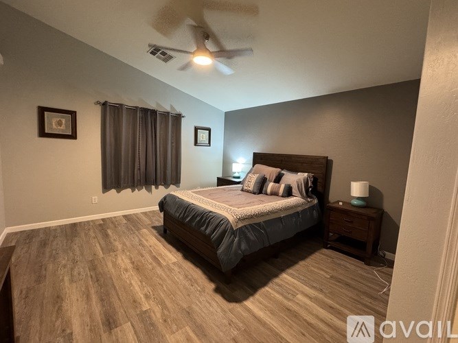 A bedroom with a bed, nightstand, and a ceiling fan.