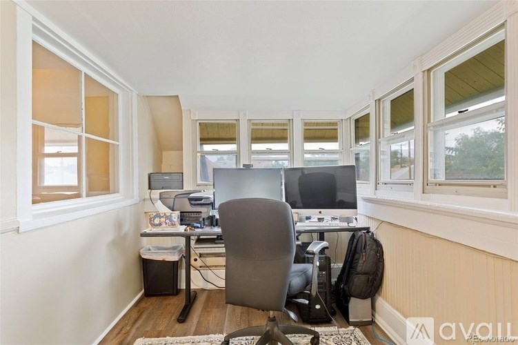 A room with a desk, computer, and chair.