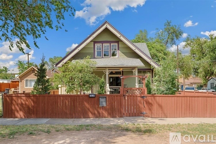 A house with a brown fence in front of it is for sale.