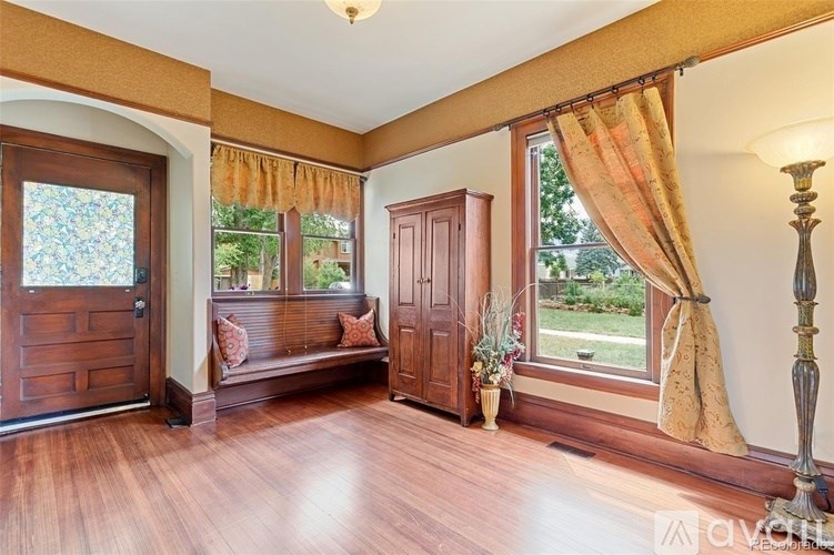A room with wooden floors and a window with curtains.