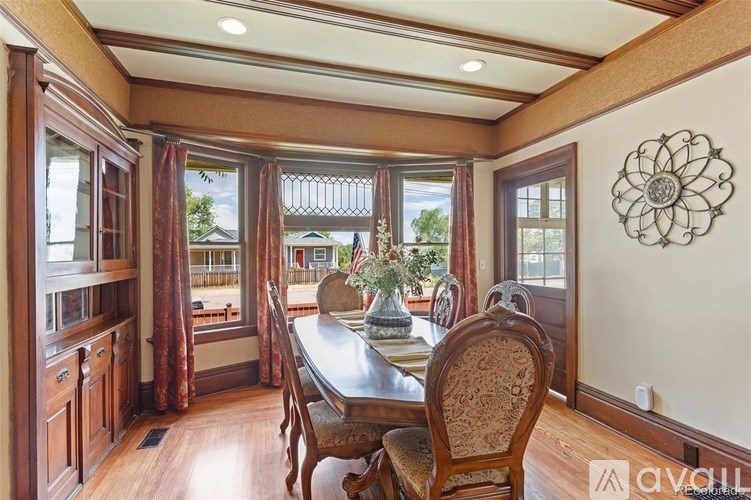 A dining room with a table and chairs and a window with curtains.