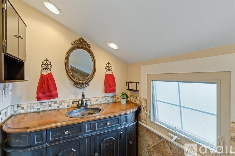 A bathroom with a black vanity and a round mirror above the sink.