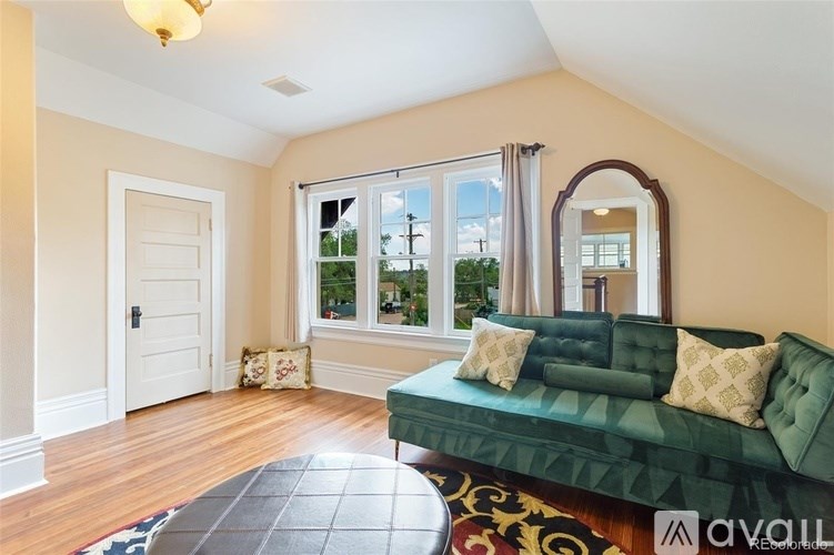 A living room with a green couch and a mirror on the wall.