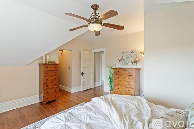 A bedroom with a bed, dresser, and ceiling fan.