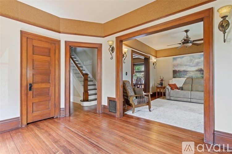 A living room with a wooden floor and a staircase in the background.