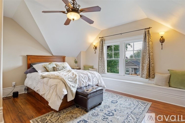 A bedroom with a bed, a ceiling fan, and a window with curtains.