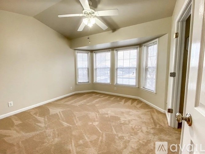 A room with a carpeted floor and a ceiling fan.