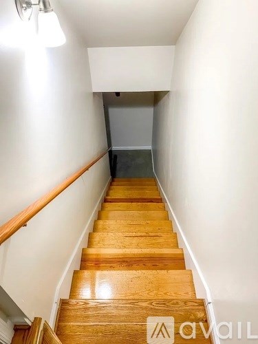 A wooden staircase with a white wall on the side and a light on.