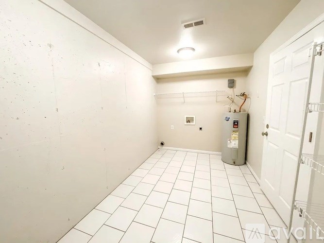 A white tiled hallway with a door on the right.