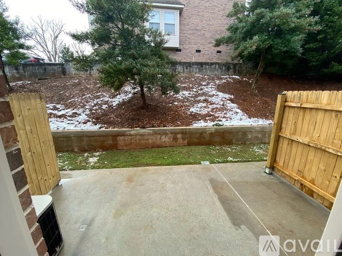 A backyard with a wooden fence and a tree in the middle.