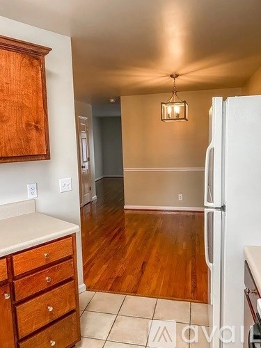 A kitchen with a white fridge, wooden cabinets and a tiled floor.