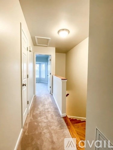 A hallway with a door on the left and a window in the distance.