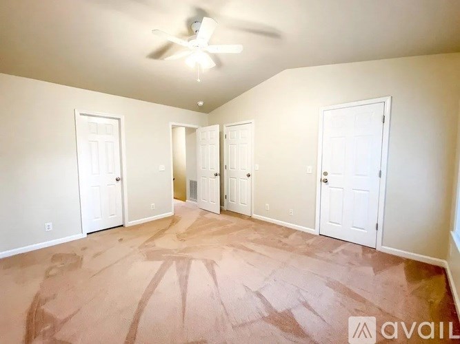 A room with a carpeted floor and a ceiling fan.