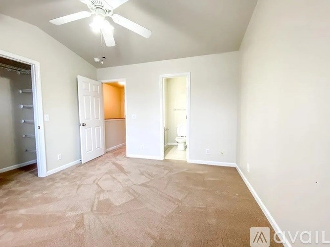 A room with a ceiling fan and carpeted floor.