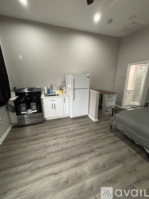 A kitchen area with a fridge, stove, and a bed.