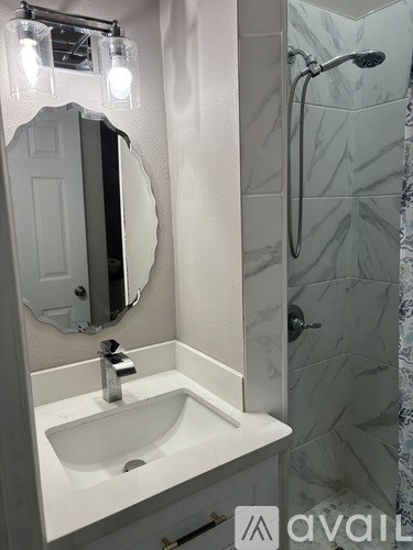 A bathroom with a sink, mirror, and shower.