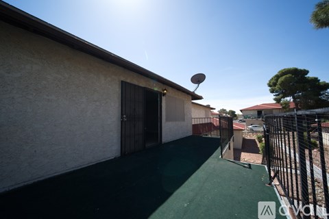 A patio area with a black gate and a green surface.