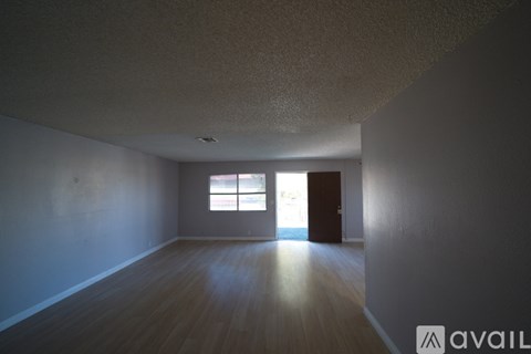 A room with wooden floors and a window letting in sunlight.