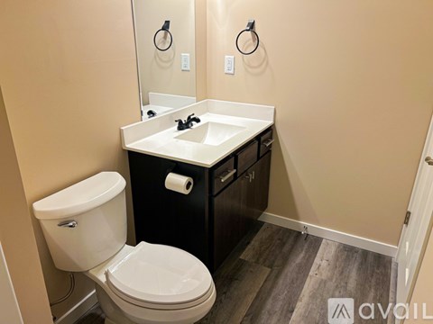 A bathroom with a toilet, sink, and mirror.