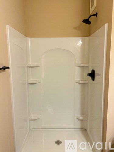 A white shower stall with a black handle and a white door.