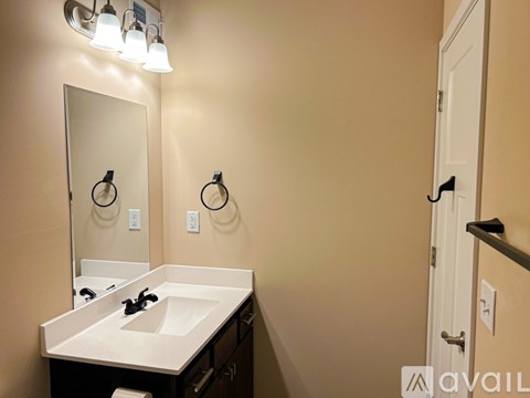 A bathroom with a sink, mirror, and light fixture.