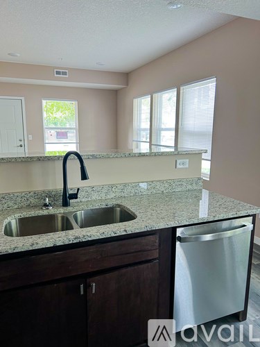 A kitchen with a granite countertop and a stainless steel dishwasher.
