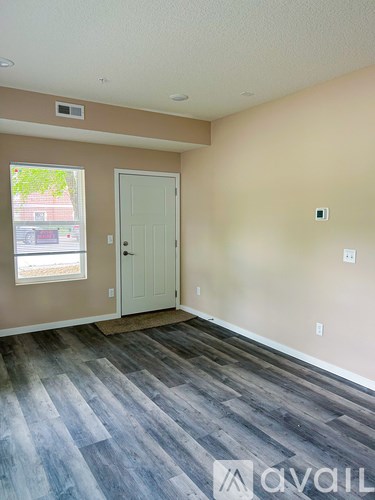 A room with a white door and a window with a view of a street.