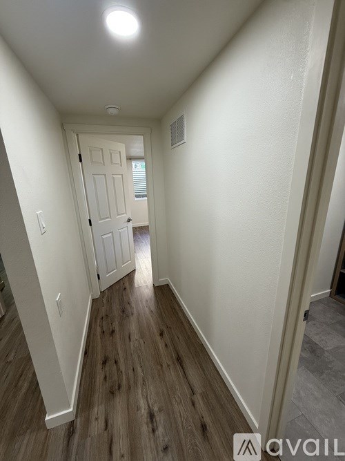 A hallway with a white door and wooden flooring.