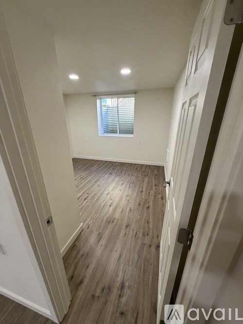 A hallway with wooden floors and white walls.