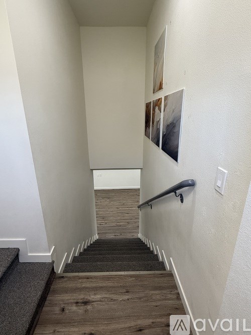 A hallway with a staircase and pictures on the wall.