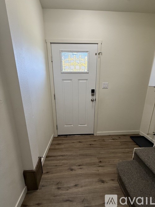 A white door with a window in the middle is in a room with wooden floors.