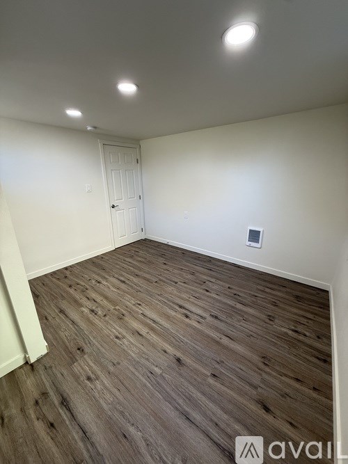 A room with wooden flooring and a white door.