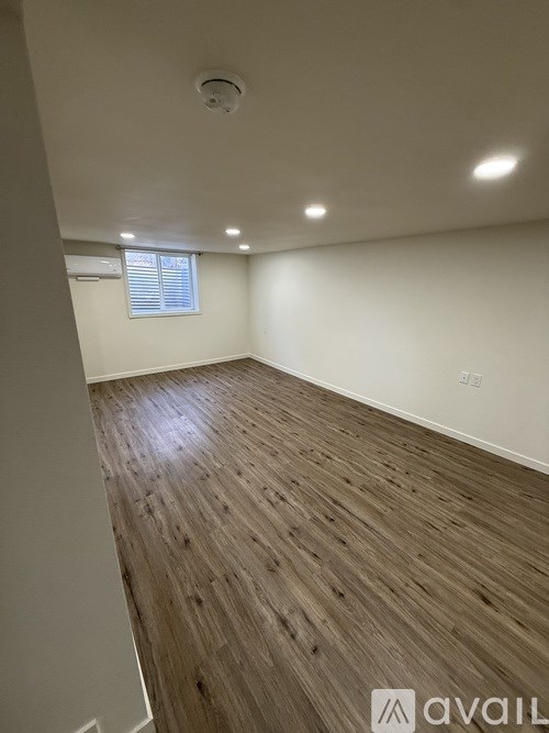 A room with wooden flooring and a window with blinds.